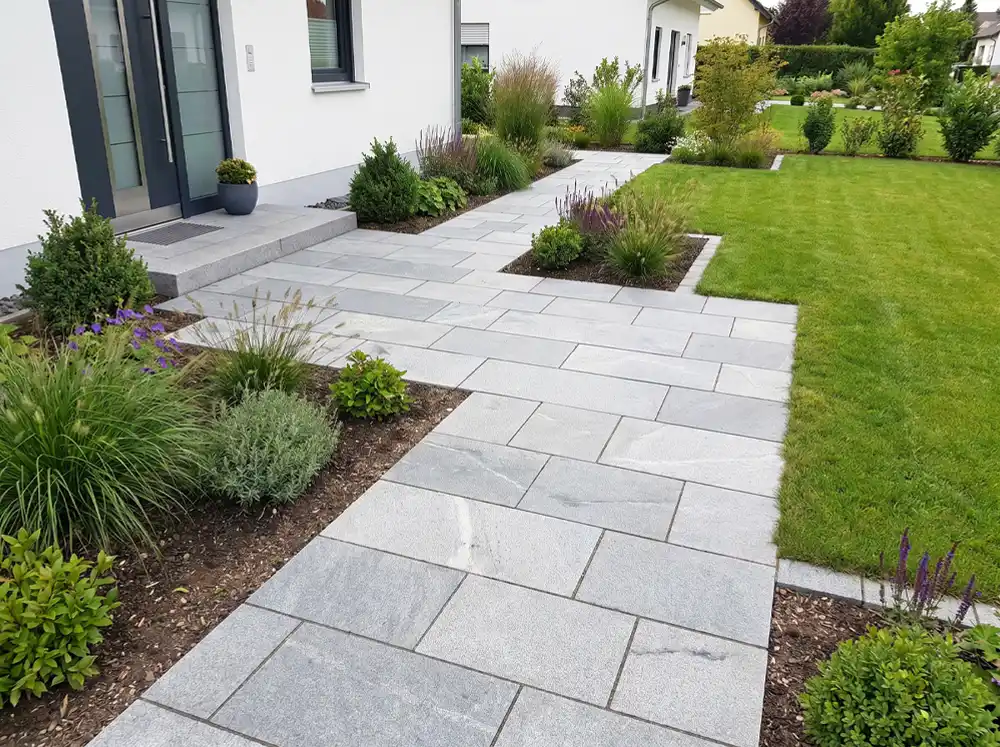 Gepflasterter Hauszugang mit Gartenweg, Beeten und sauberem Übergang zum Rasen