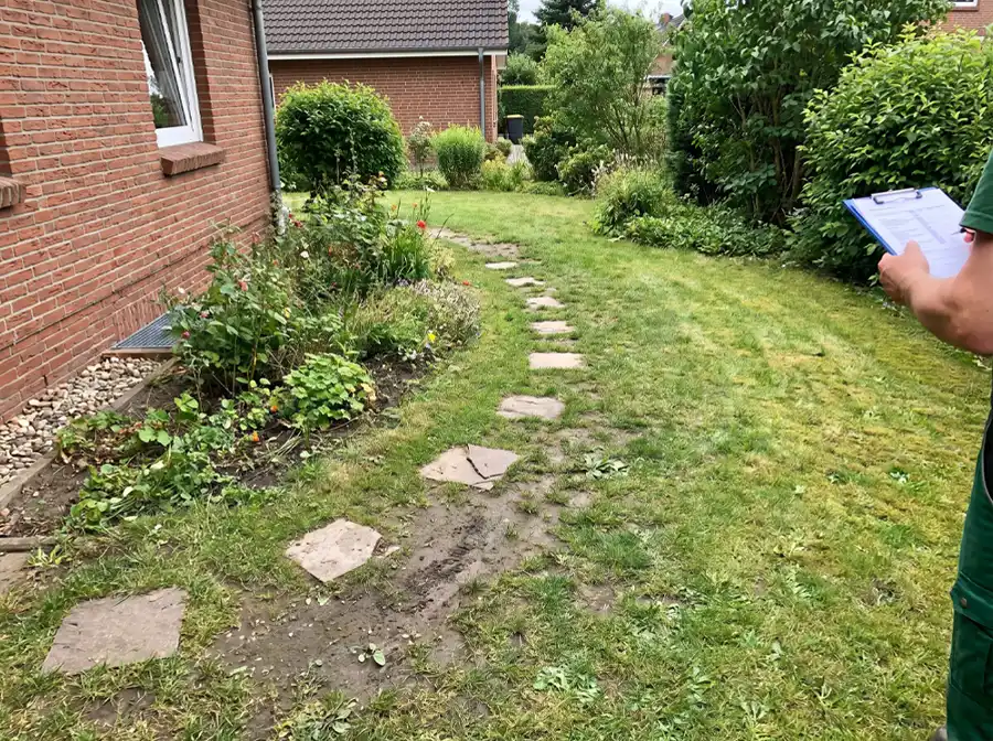Außenbereich mit unklarem Übergang zwischen Haus, Rasen und Beet vor Pflasterarbeiten